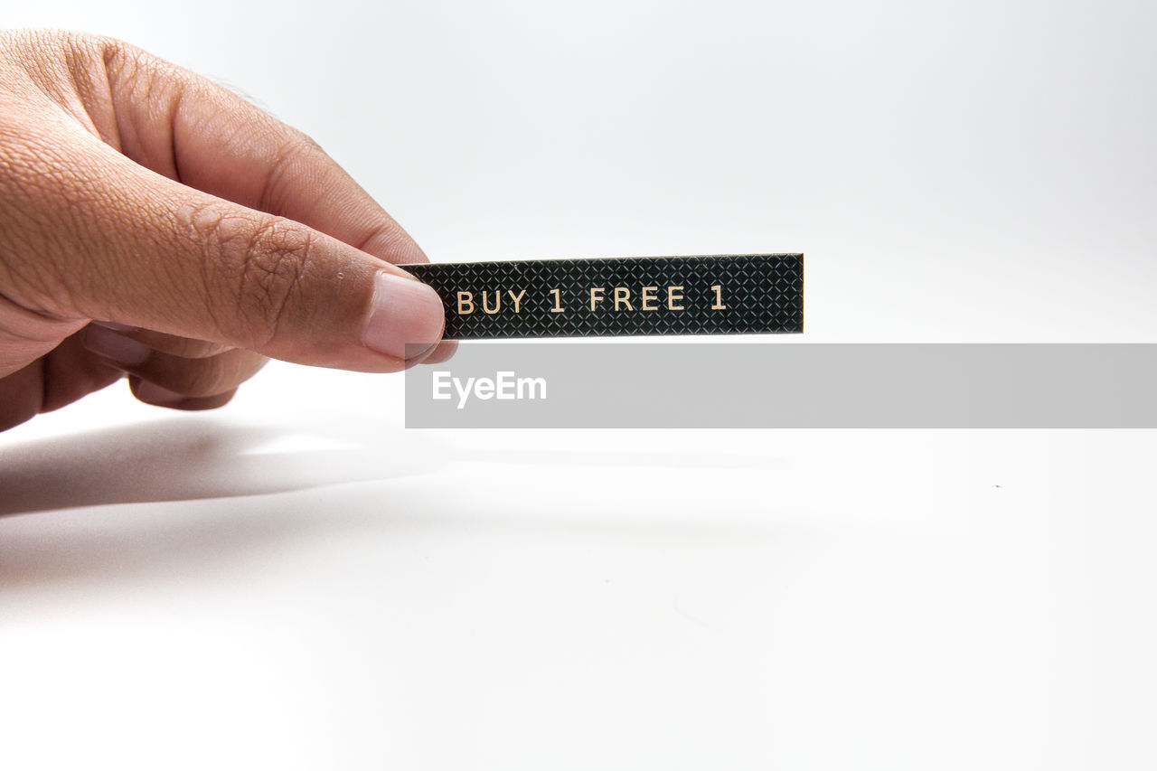 CLOSE-UP OF PERSON HAND HOLDING WHITE BACKGROUND