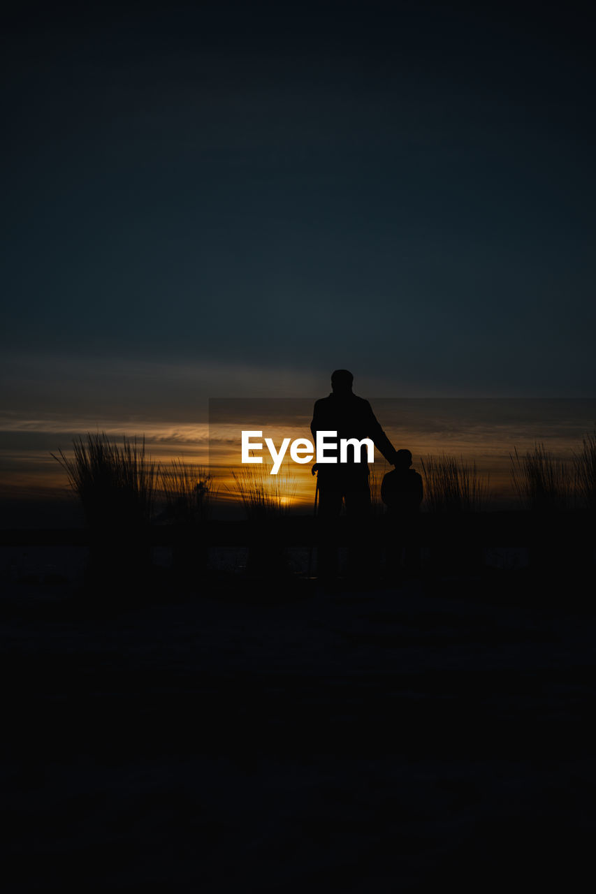 SILHOUETTE MAN STANDING ON FIELD DURING SUNSET