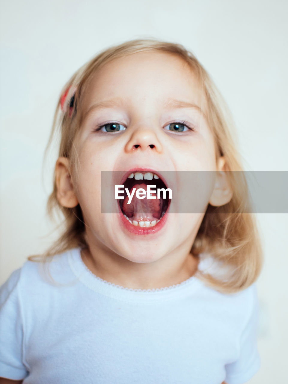 Portrait of cute girl with mouth open sitting against white background