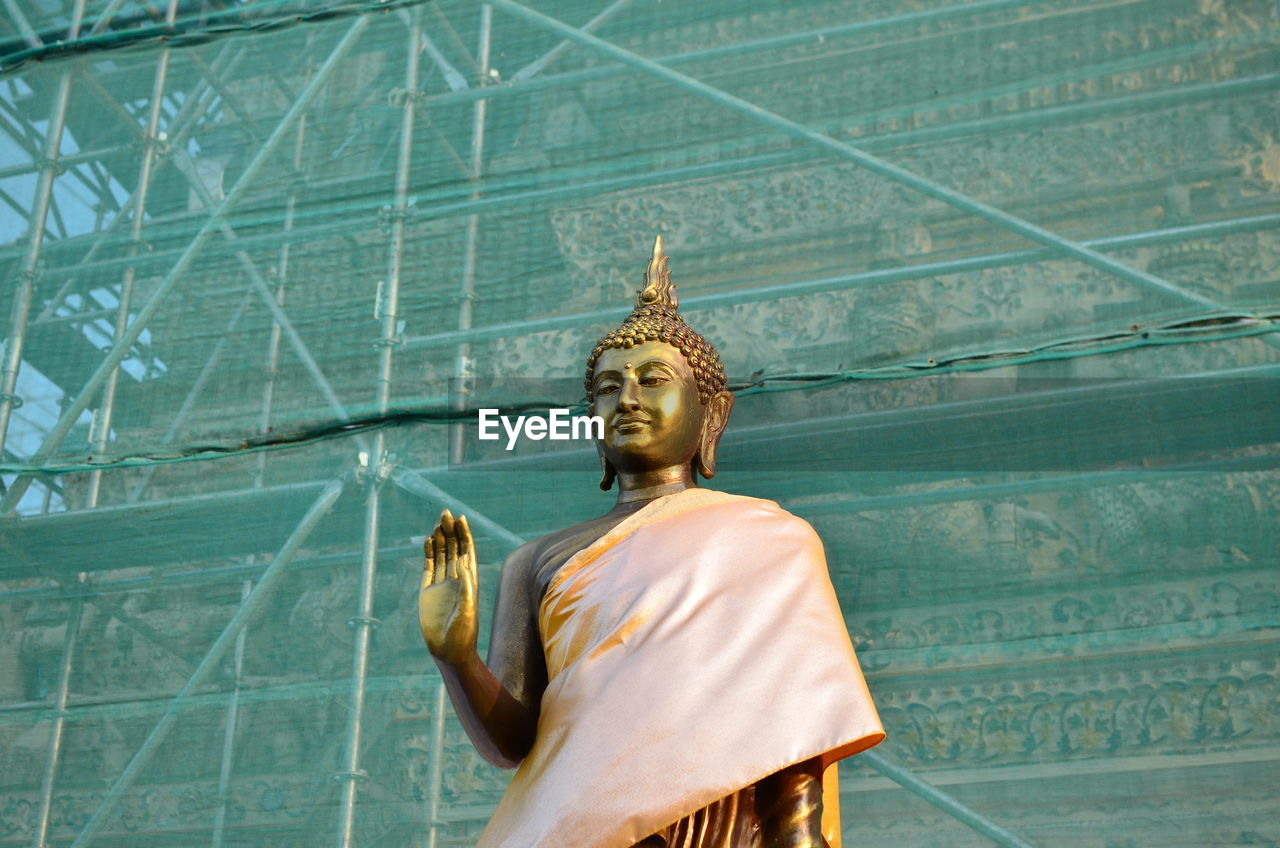 Buddha statue against scaffolding on building