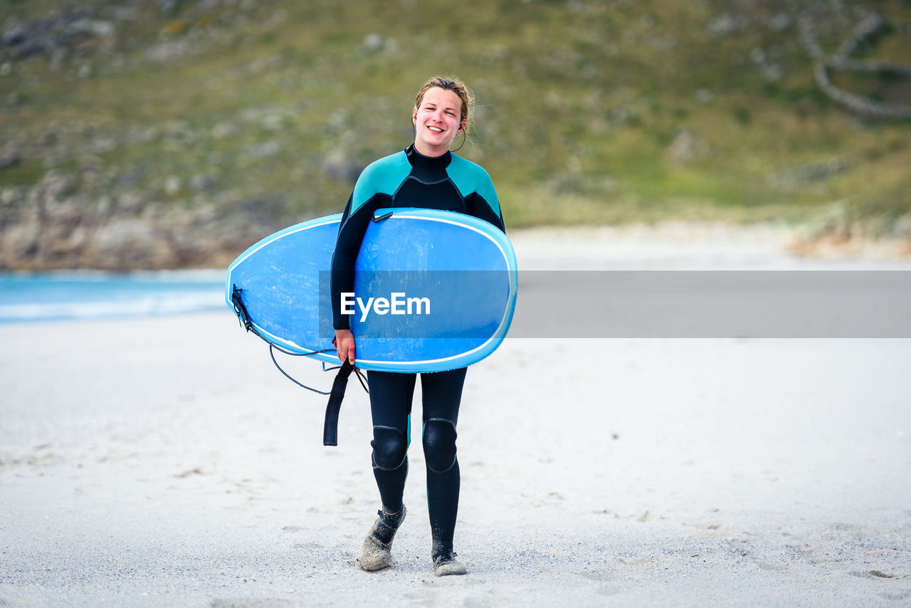 Portrait of surfer woman with surfboard standing at beach