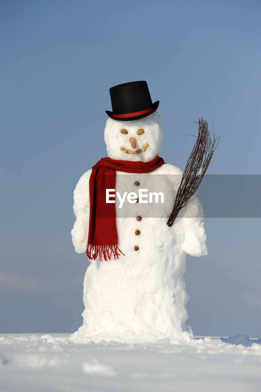 Snowman on field against blue sky