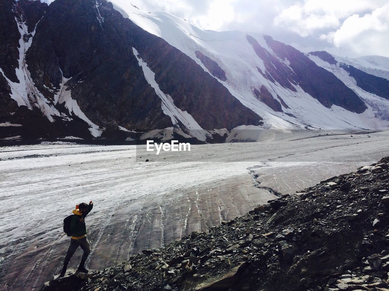 MAN WALKING ON SNOWCAPPED MOUNTAINS AGAINST SKY