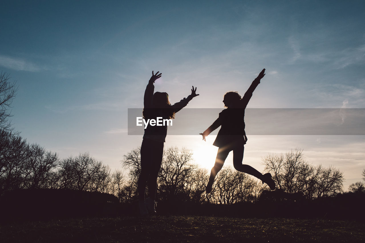 Full length of silhouette people jumping at sunset