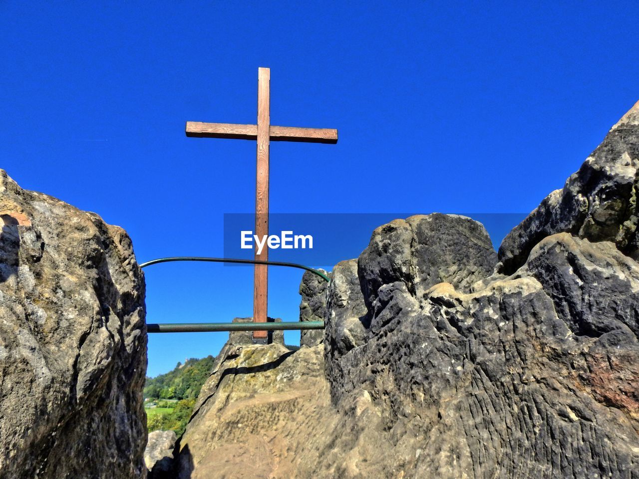 Low angle view of cross next to wall against clear sky