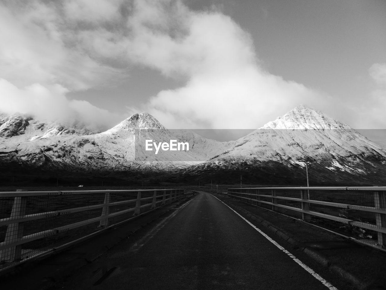 Empty road leading towards snowcapped mountains against sky