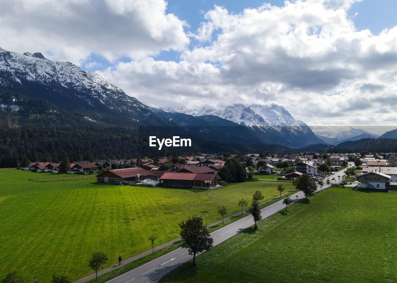 landscape, mountain, environment, scenics - nature, mountain range, sky, architecture, building, cloud, land, beauty in nature, house, nature, building exterior, built structure, plant, rural scene, field, grass, village, rural area, residential district, city, travel, travel destinations, snow, green, agriculture, no people, tranquility, water, highland, valley, tourism, farm, outdoors, tranquil scene, tree, snowcapped mountain, cold temperature, winter, meadow, road, day, idyllic, town, aerial photography, transportation, social issues, plain, springtime, activity, vacation, high angle view