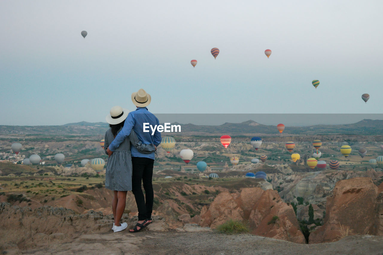 rear view of woman with balloons on landscape against sky