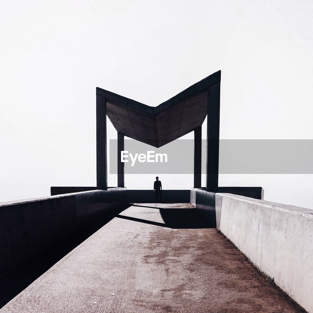 Silhouette of man standing at built structure against clear sky