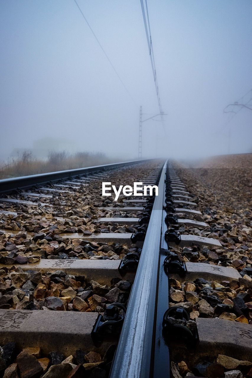 Surface level of railroad tracks against sky during winter