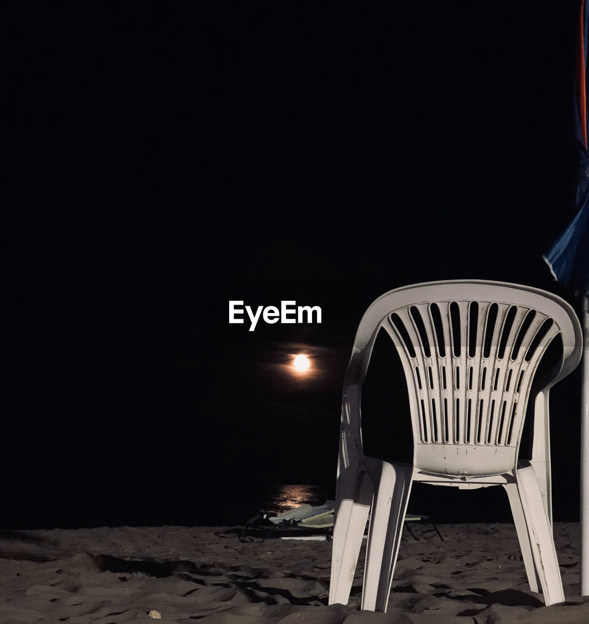 Empty chairs at beach against clear sky at night