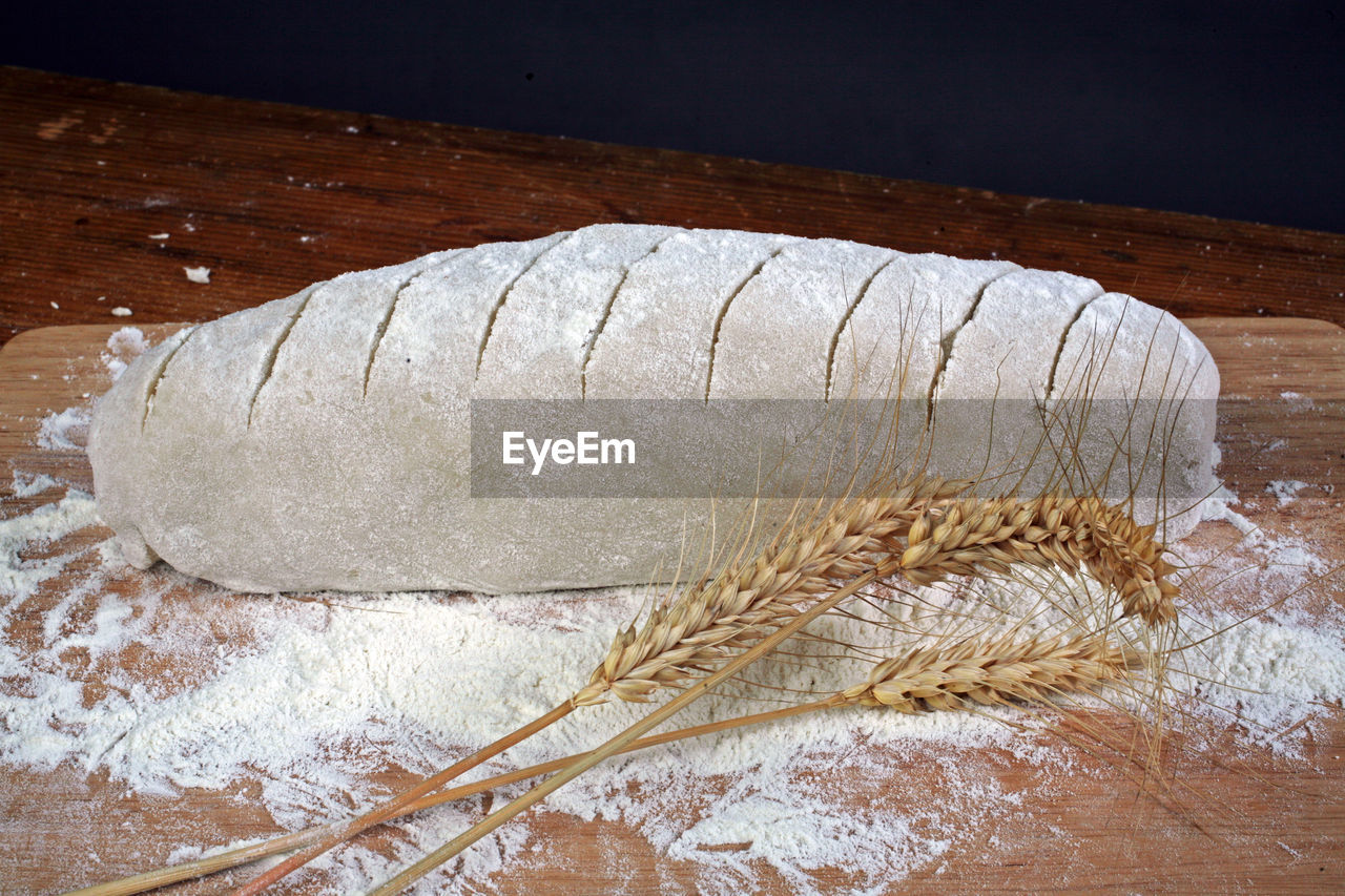 Flour on bread loaf next to wheat crop