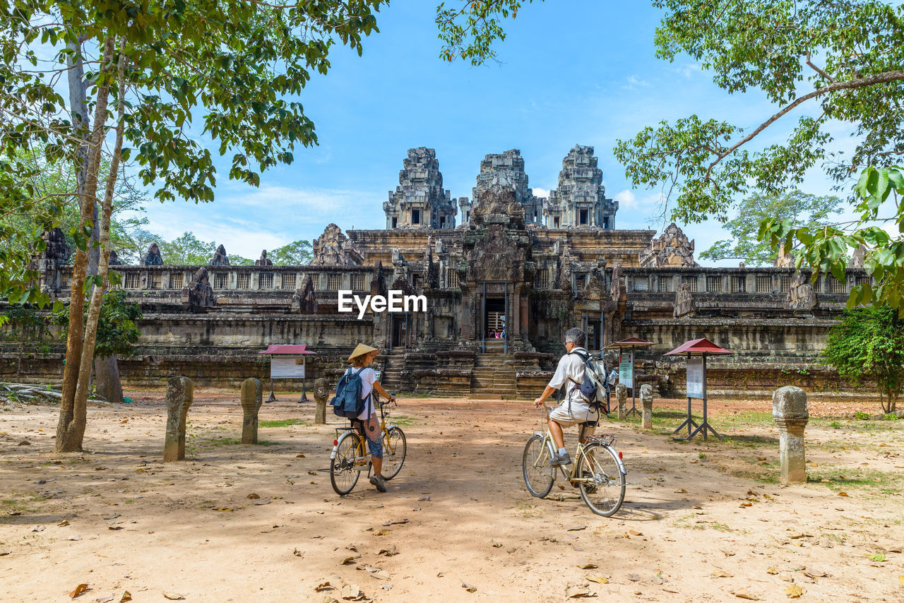 Full length of tourists cycling at temple