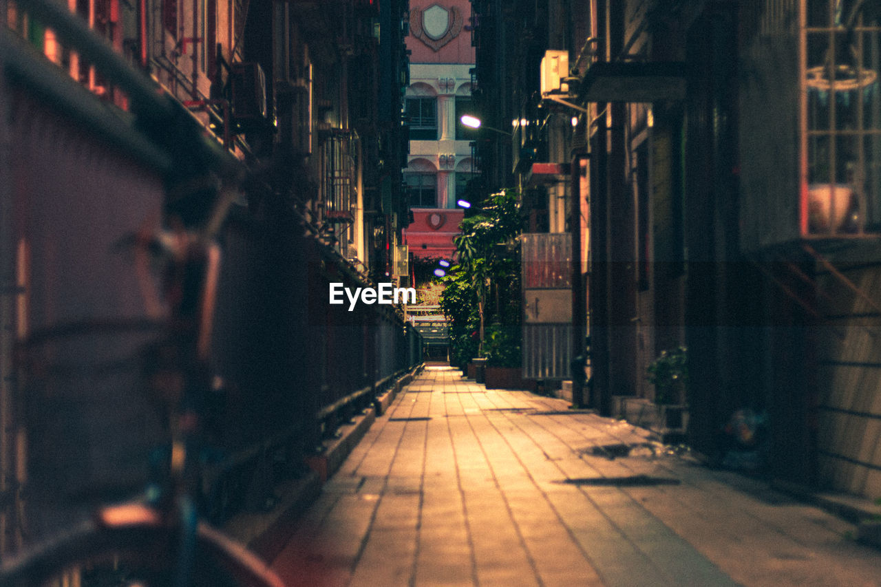 Illuminated alley amidst buildings at night