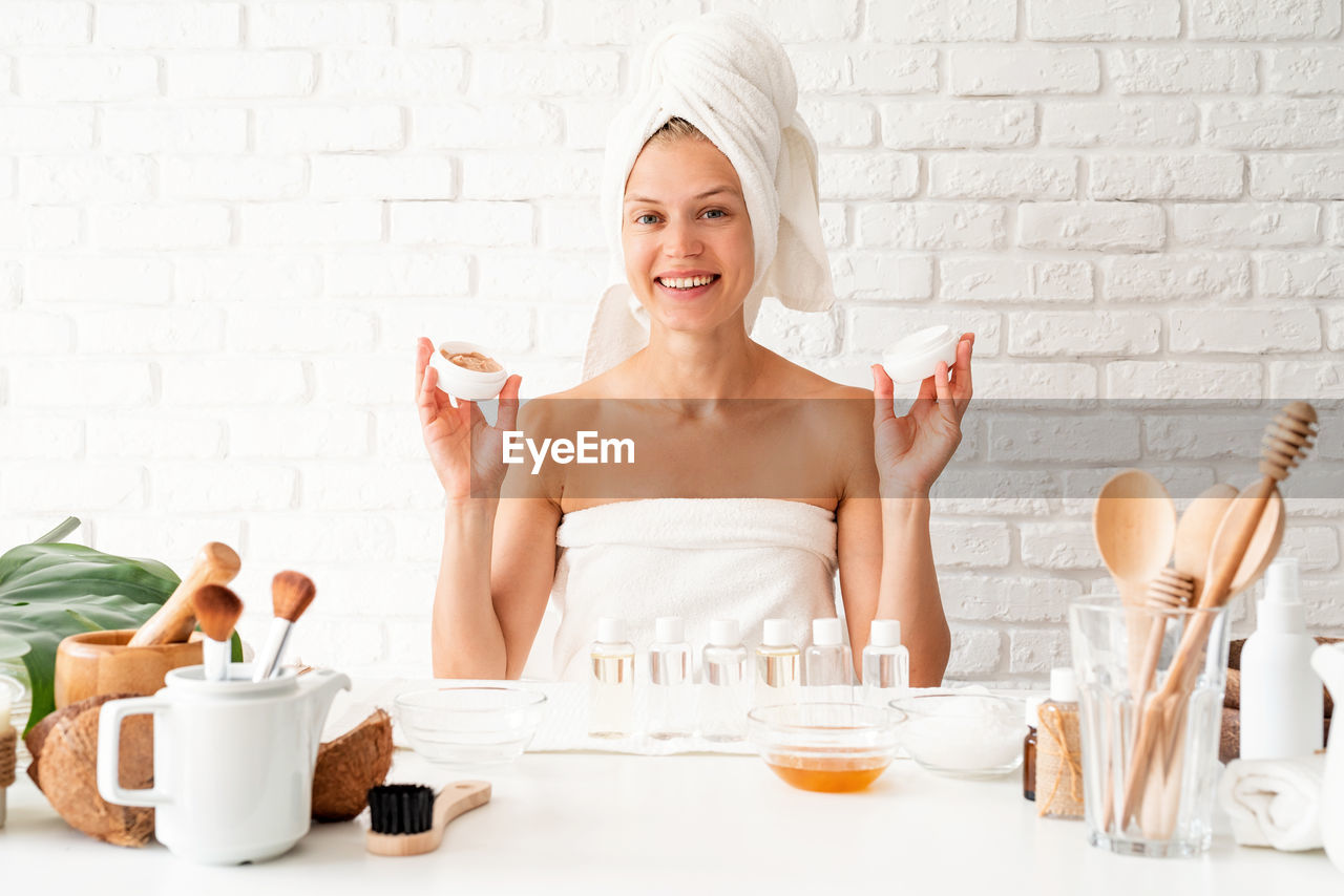 Self care. happy young woman wearing white bathrobes towels on head doing spa procedures in spa