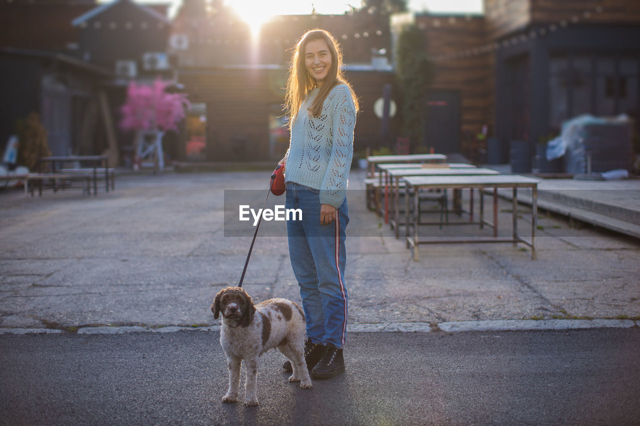 Portrait of woman with dog standing on road