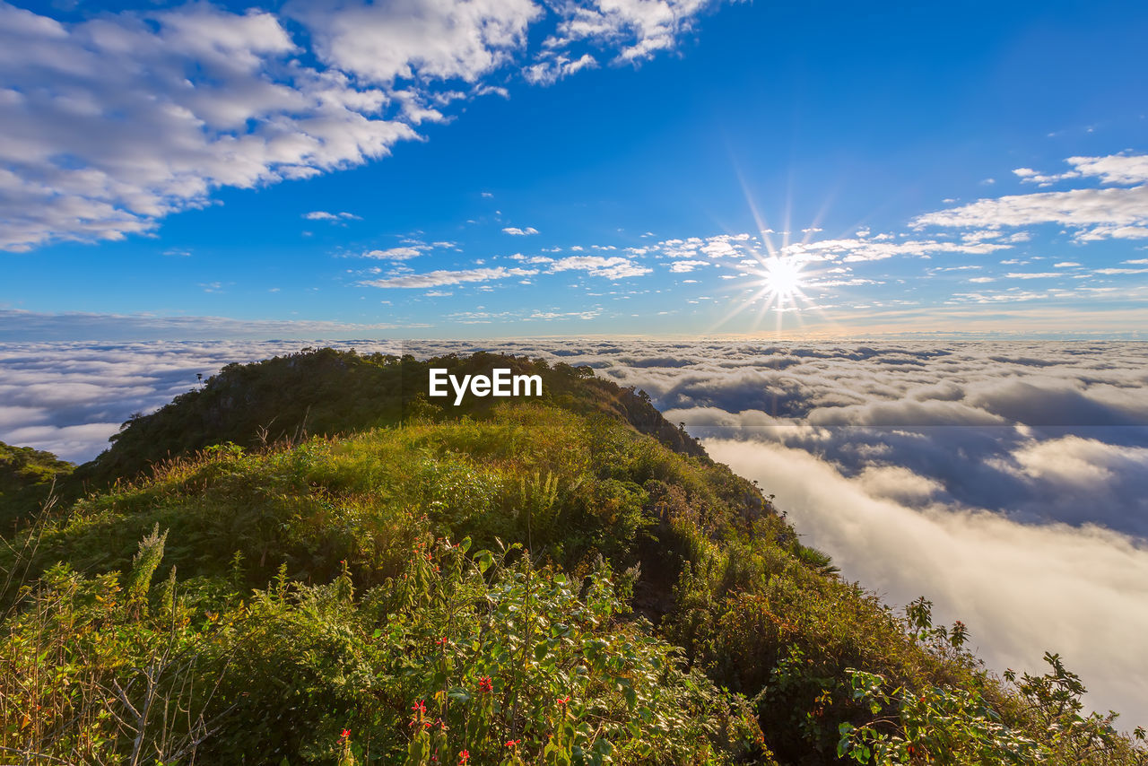 Scenic view of mountains against cloudy sky during sunny day