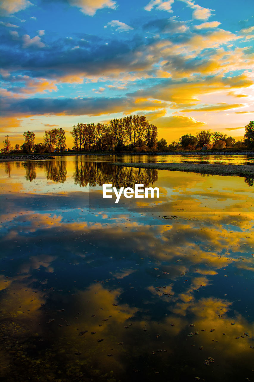 SCENIC VIEW OF LAKE BY TREES AGAINST SKY DURING SUNSET