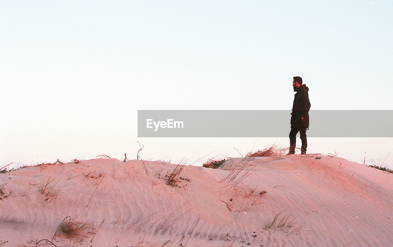 Full length of man standing on desert against clear sky