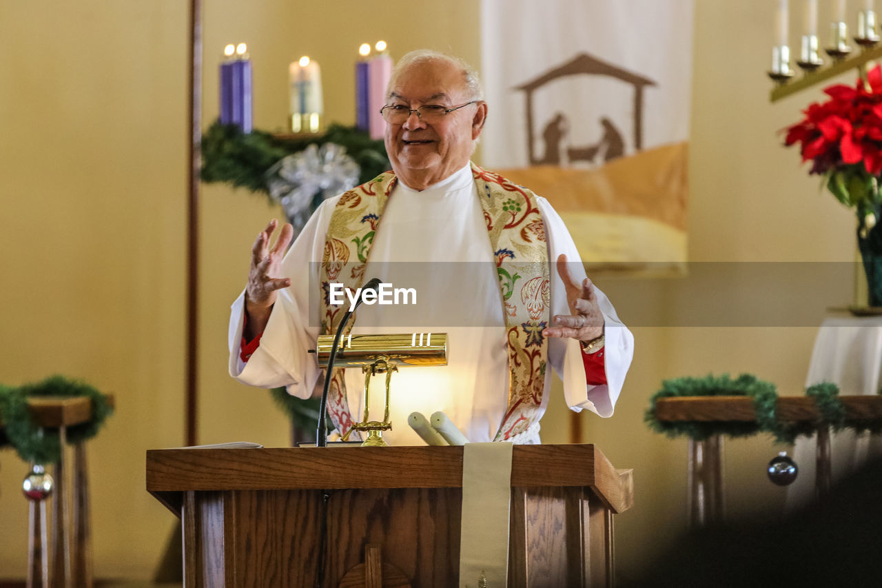 Smiling priest giving speech in church