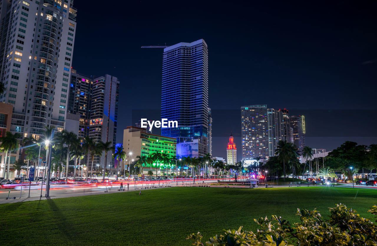 architecture, building exterior, built structure, city, office building exterior, night, skyscraper, building, skyline, illuminated, landscape, metropolitan area, cityscape, urban skyline, sky, residential district, metropolis, urban area, travel destinations, nature, office, grass, downtown district, plant, city life, landmark, downtown, outdoors, tower block, travel, lighting equipment, street, development, tree, park - man made space, park, crowd, tower, city street, sports, horizon