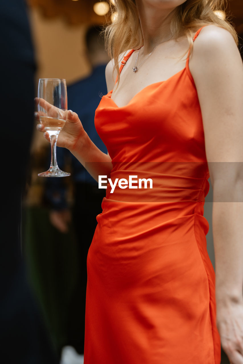 midsection of woman holding wineglass while sitting on table