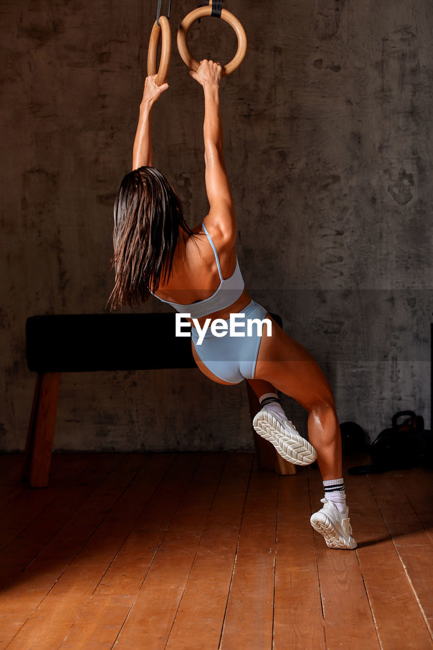 Rear view of woman exercising on floor