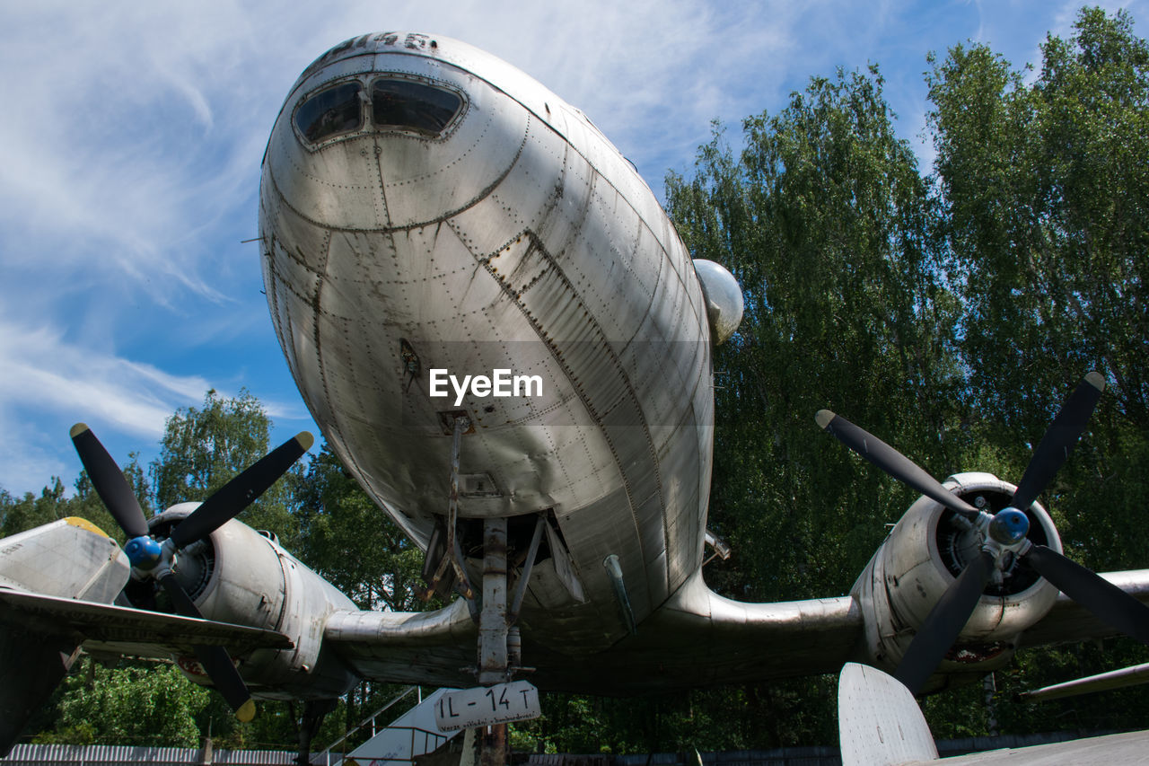 LOW ANGLE VIEW OF SCULPTURE AND AIRPLANE AGAINST SKY