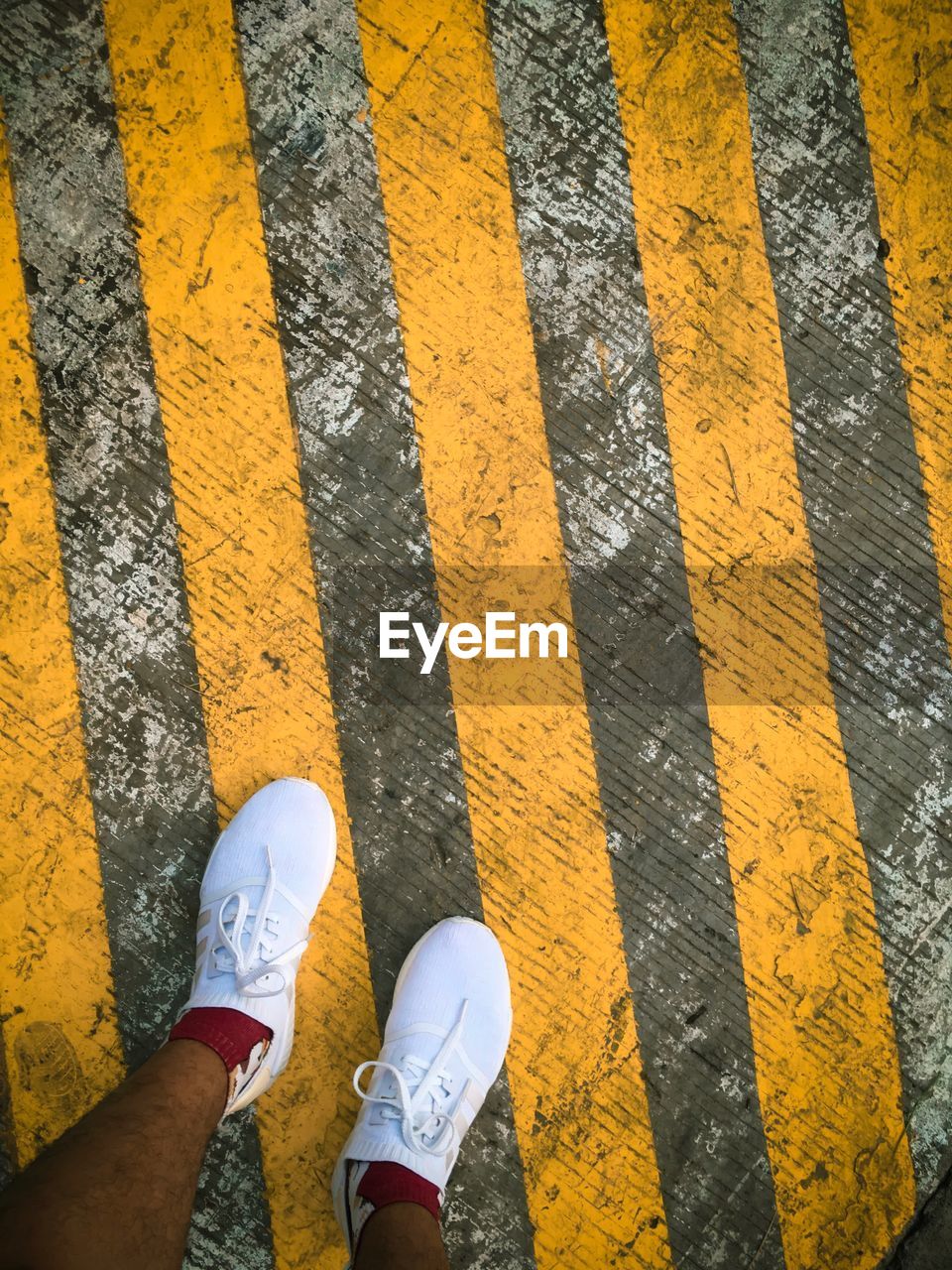 LOW SECTION OF PERSON STANDING ON ZEBRA CROSSING