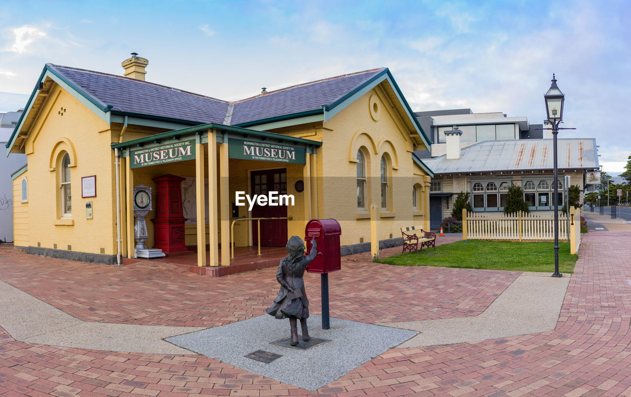 FULL LENGTH OF MAN STANDING ON FOOTPATH AGAINST BUILDINGS