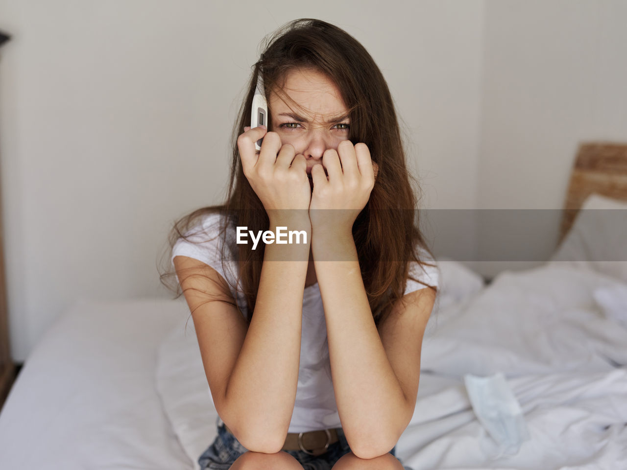 Portrait of young woman sitting on bed at home