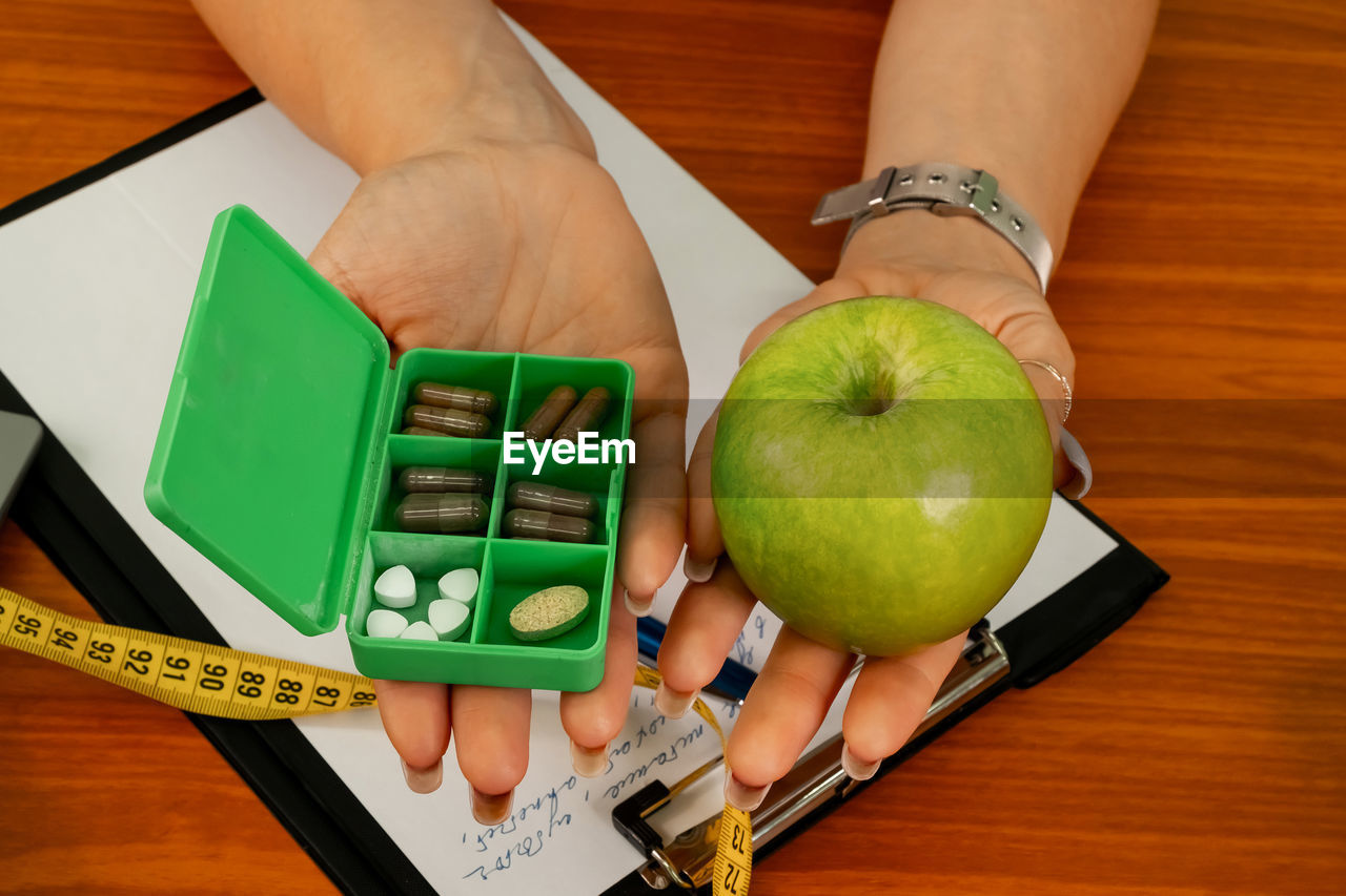 Doctor holding apple or dietary food supplement pills.