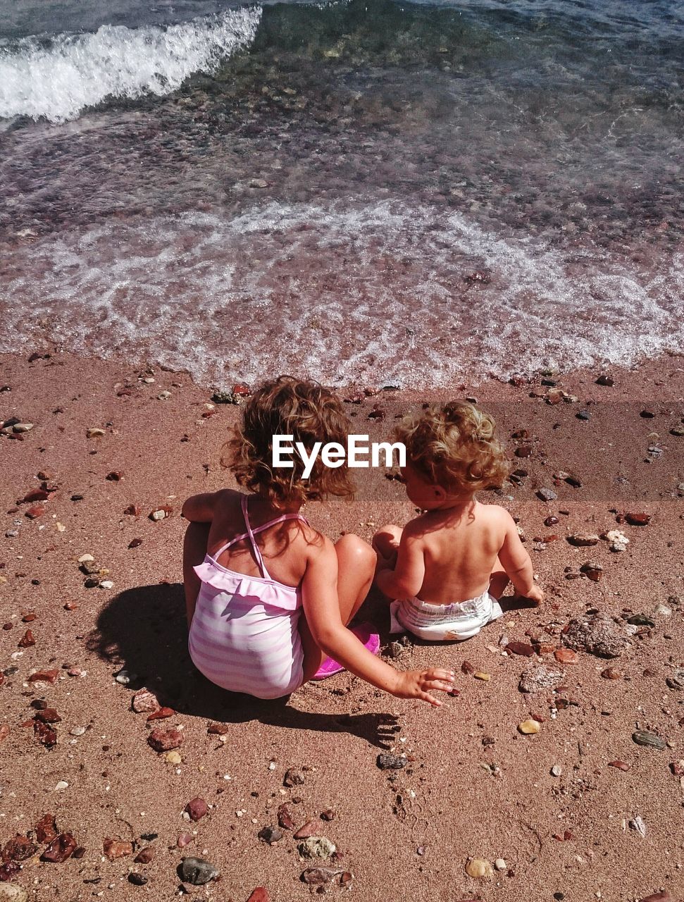 High angle view of sisters sitting on beach