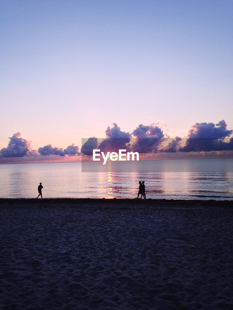 People walking at beach during sunrise