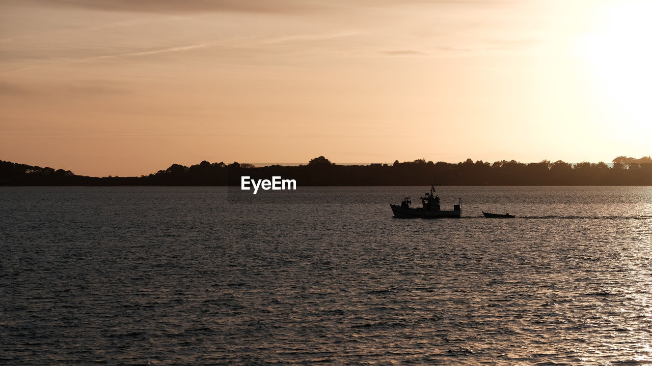 Silhouette boats sailing in sea against sky during sunset