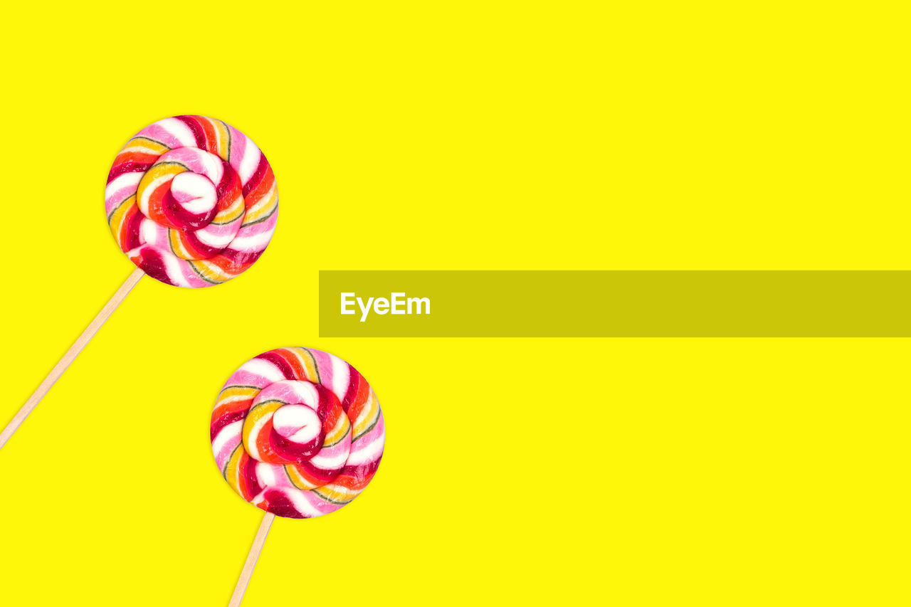 Close-up of multi colored candies against yellow background