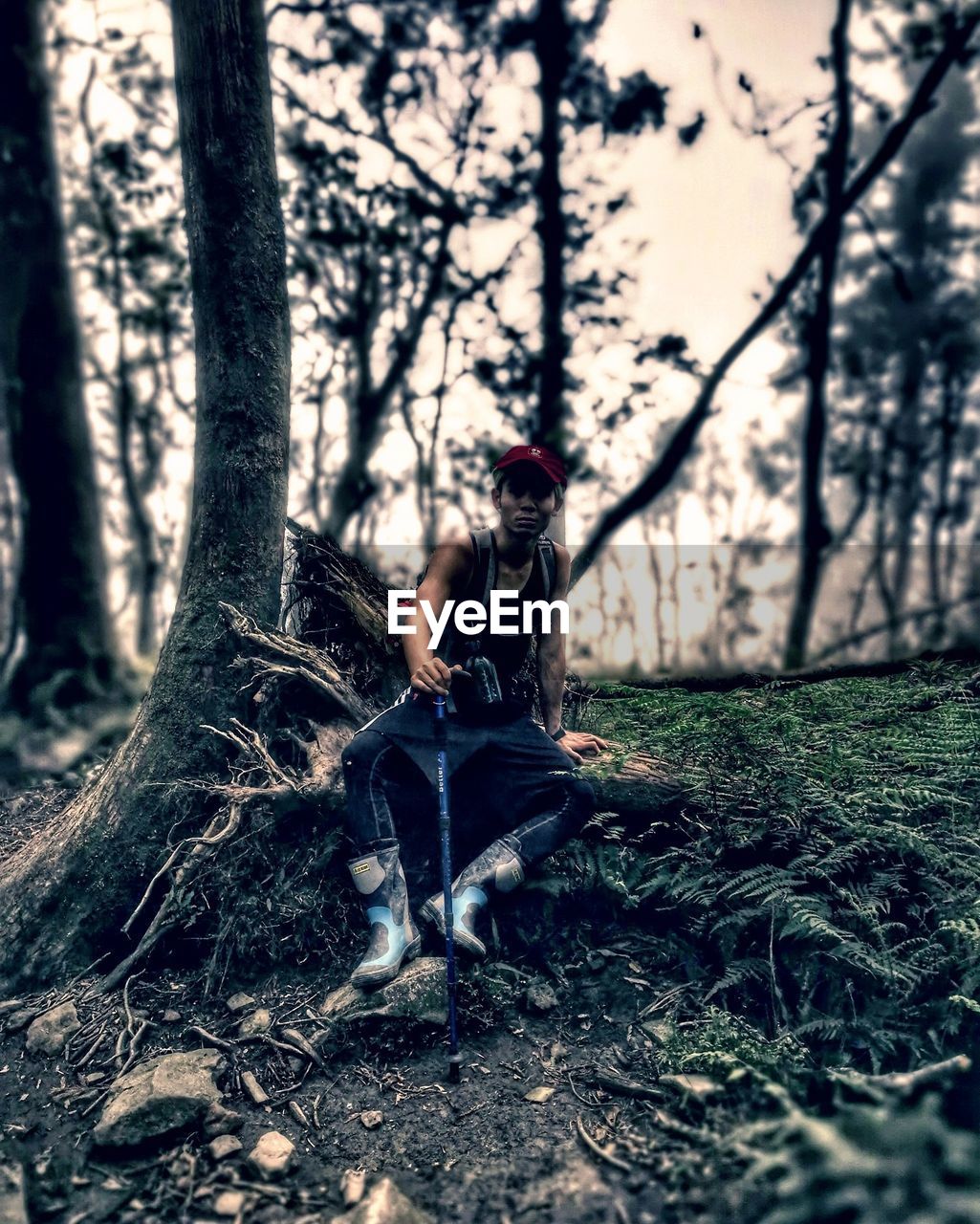 WOMAN SITTING ON TREE TRUNK IN FOREST