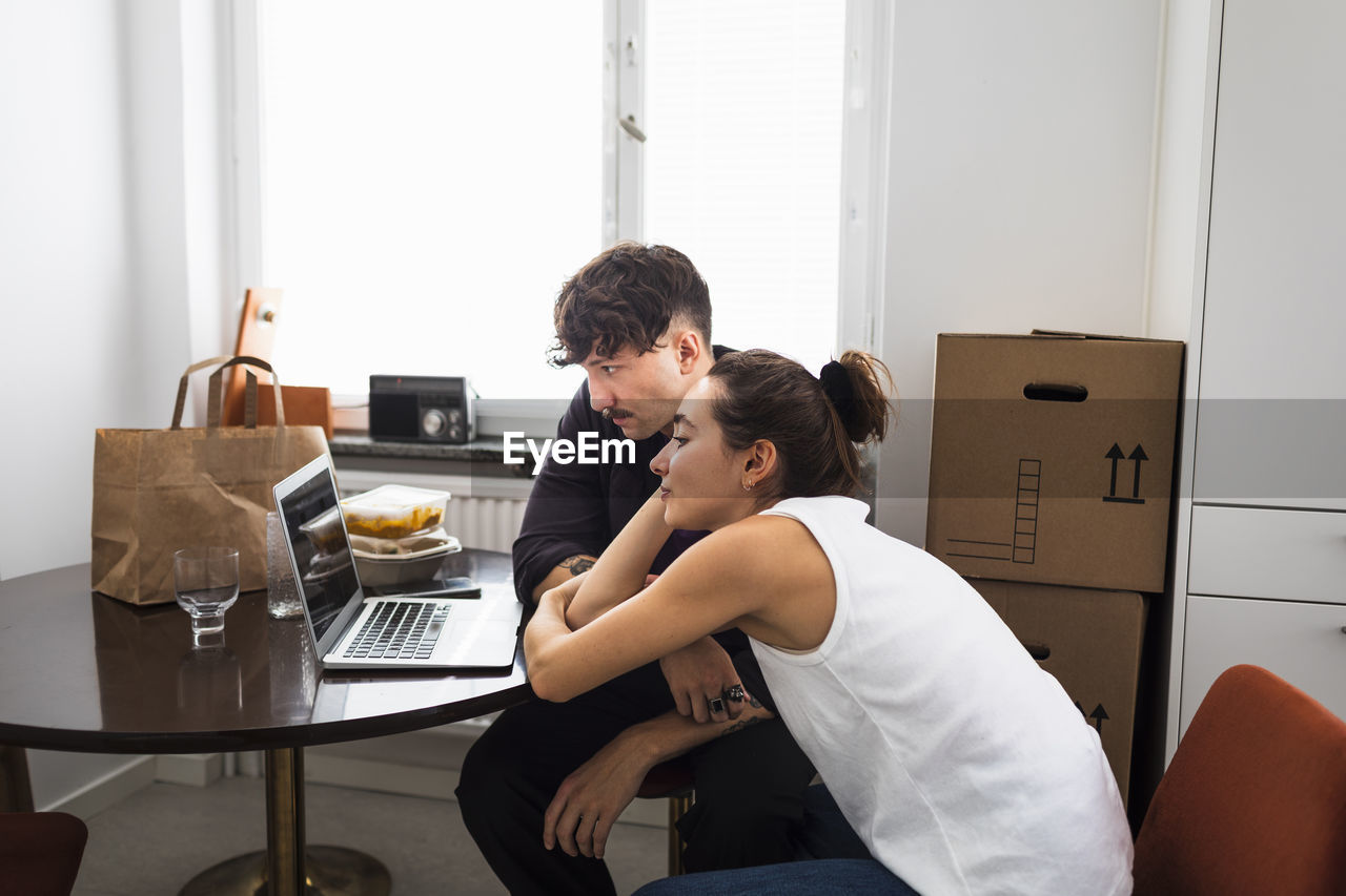Couple sitting at table and using laptop