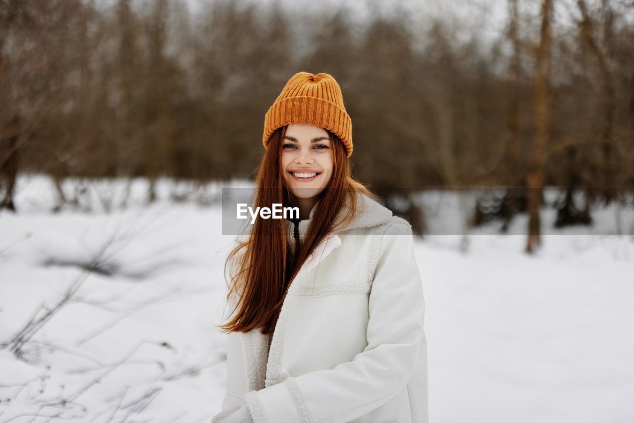 Portrait of smiling young woman standing on snow