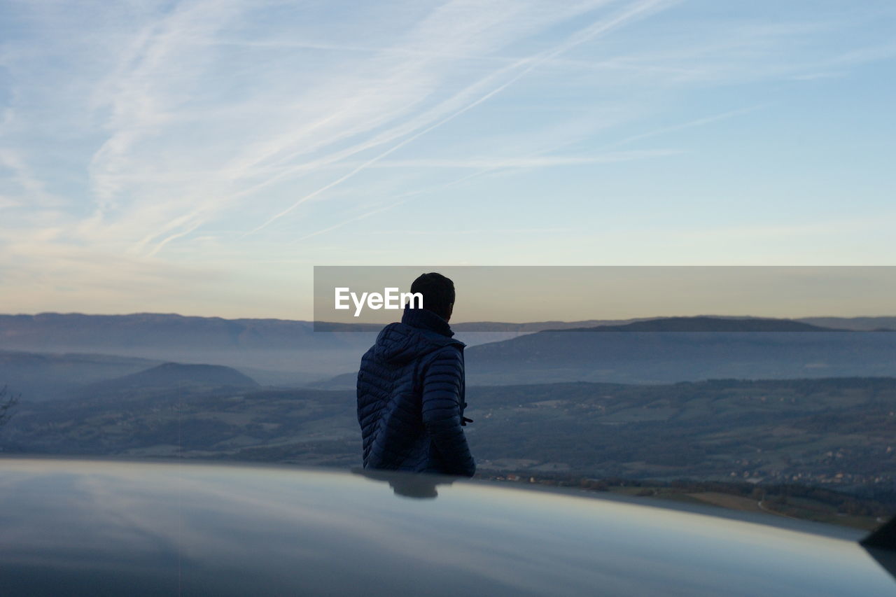 Rear view of man on mountain against sky during sunset