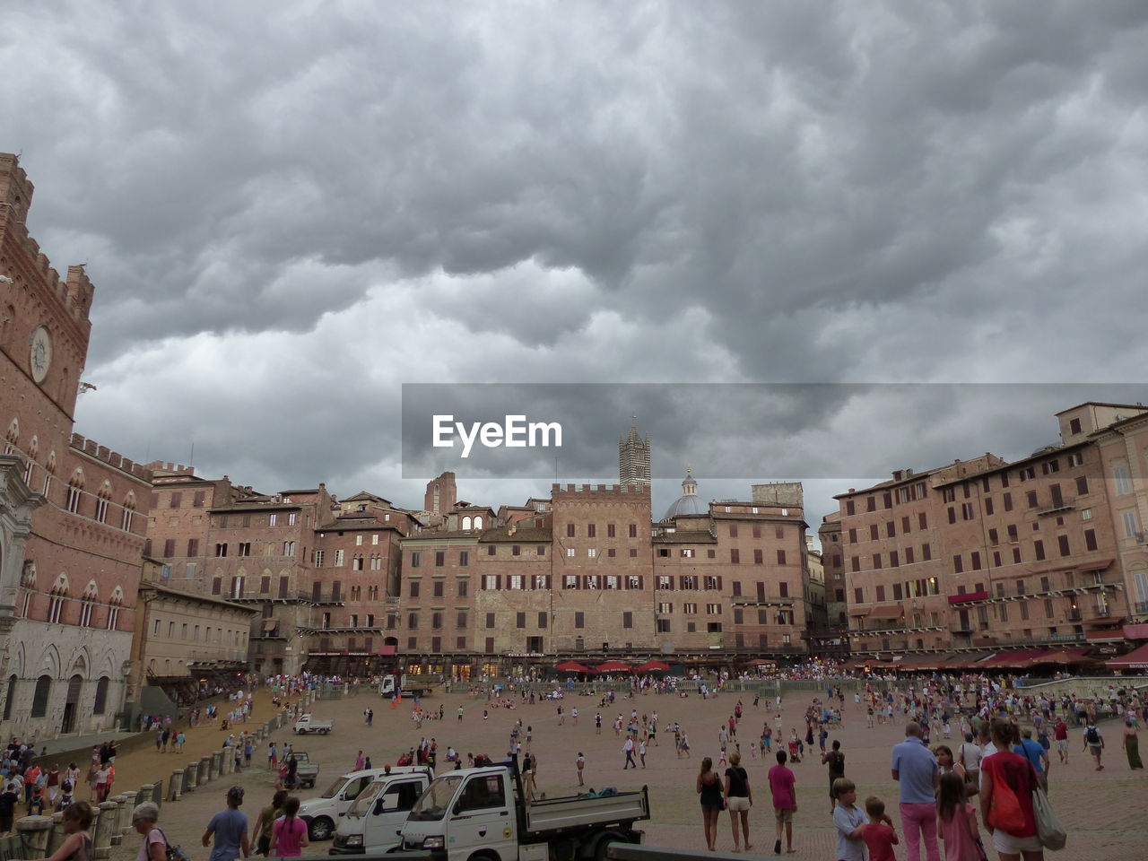 People at town square against cloudy sky