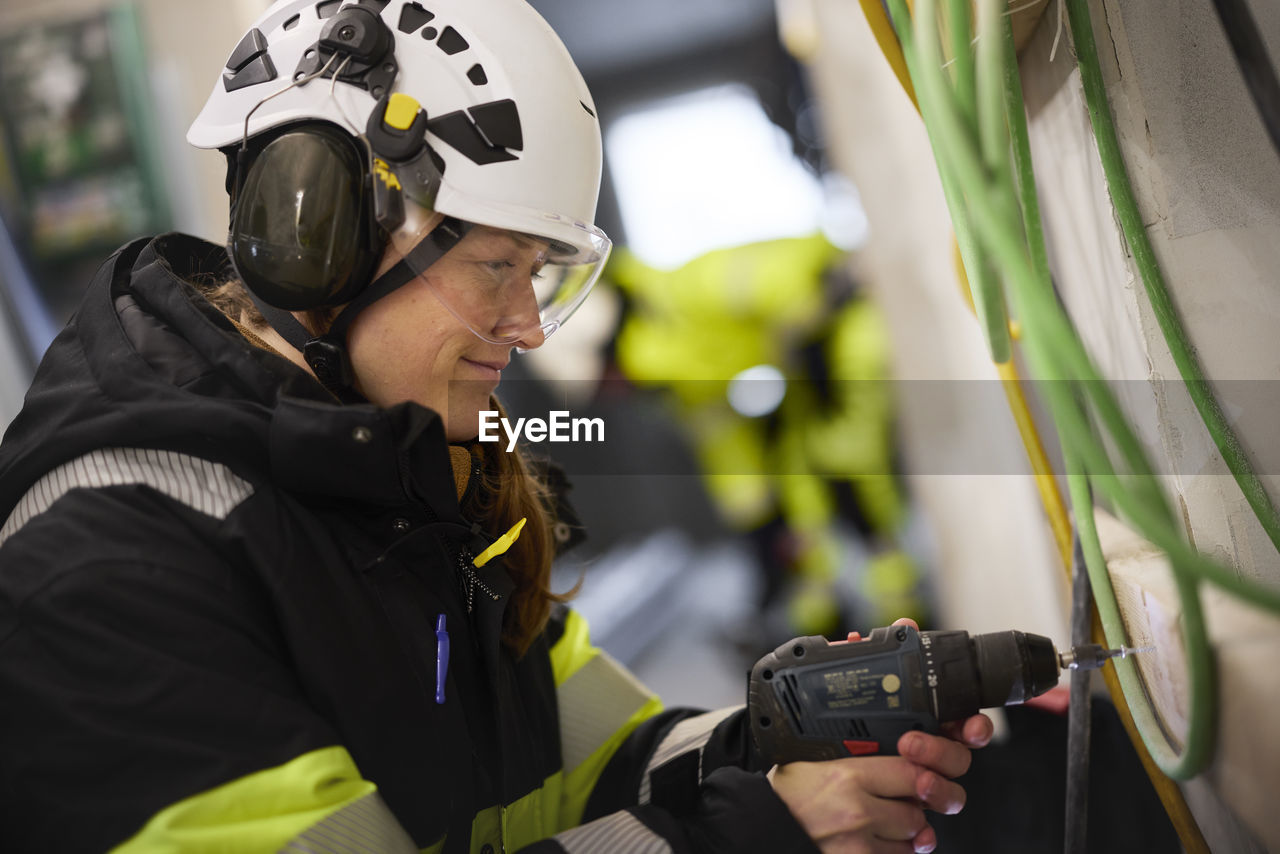 Female construction worker using electric drill