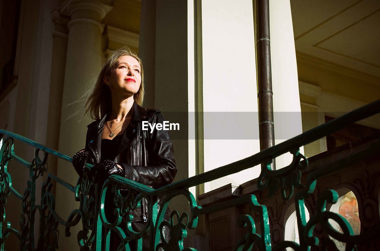 Portrait of young woman standing against railing