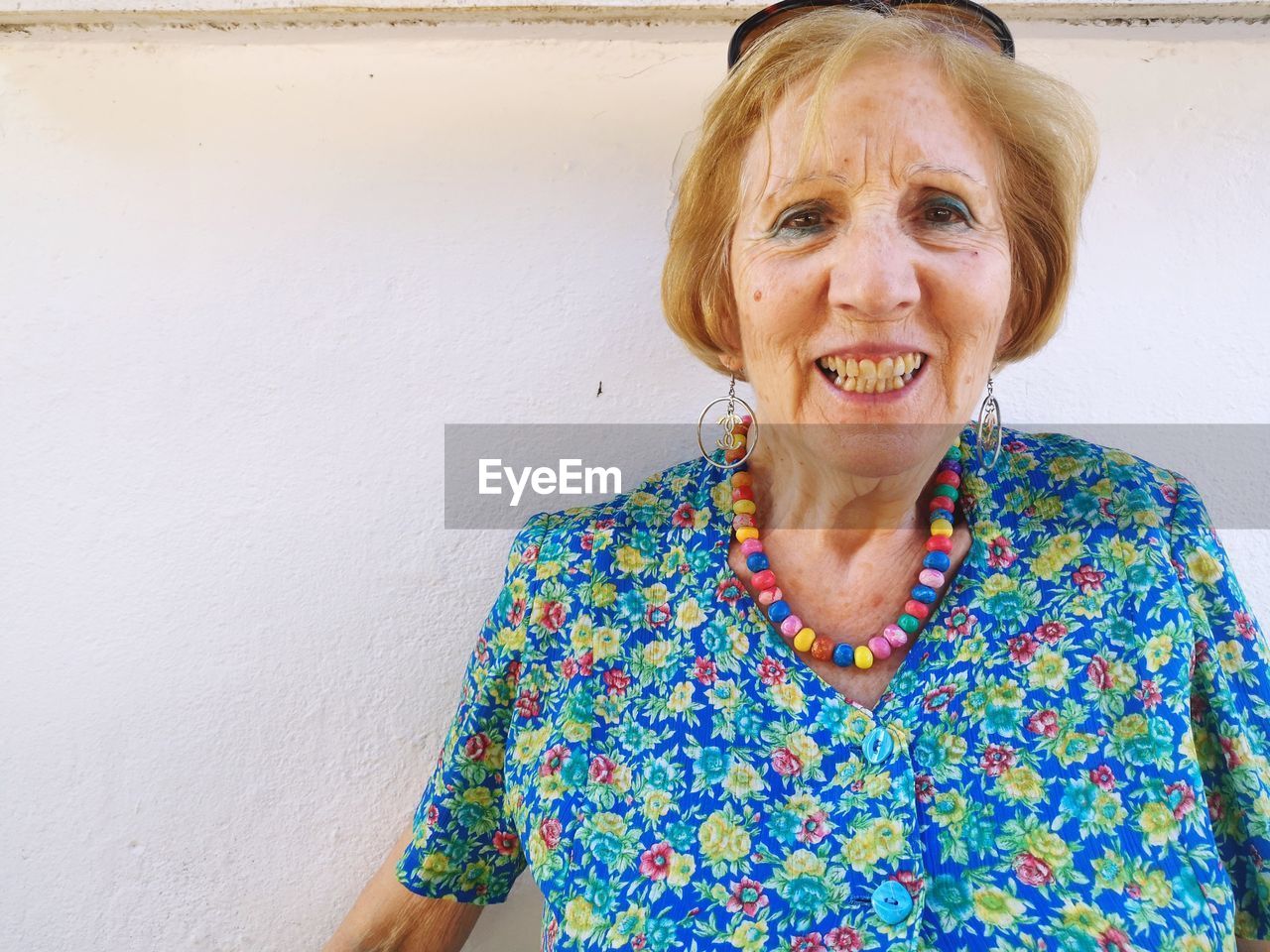 PORTRAIT OF HAPPY WOMAN STANDING AGAINST WALL