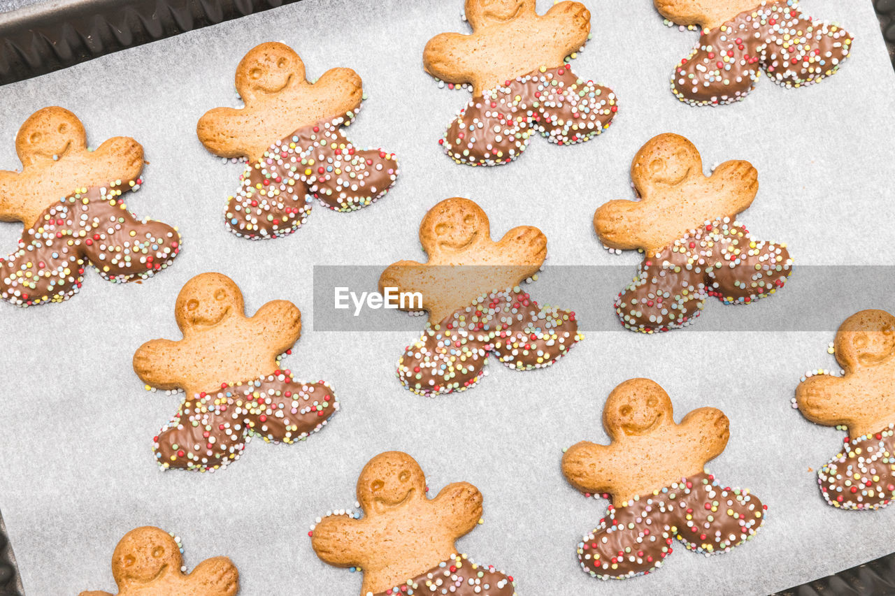 Three diagonal rows of gingerbread men on baking paper in a baking dish