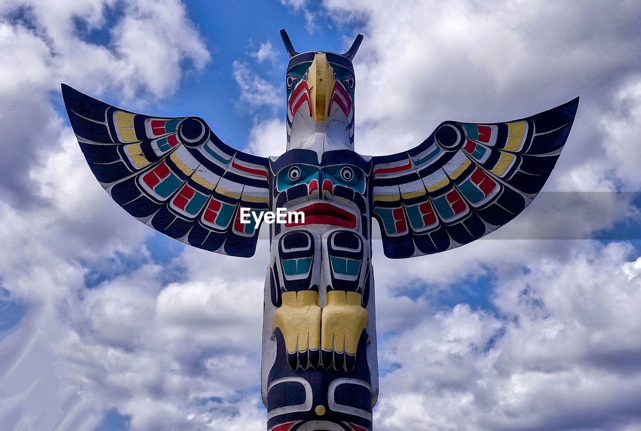 Low angle view of totem pole against cloudy sky