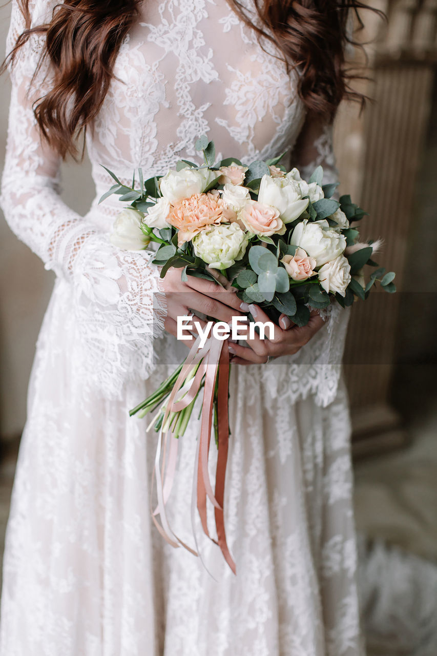 Midsection of bride holding flower bouquet