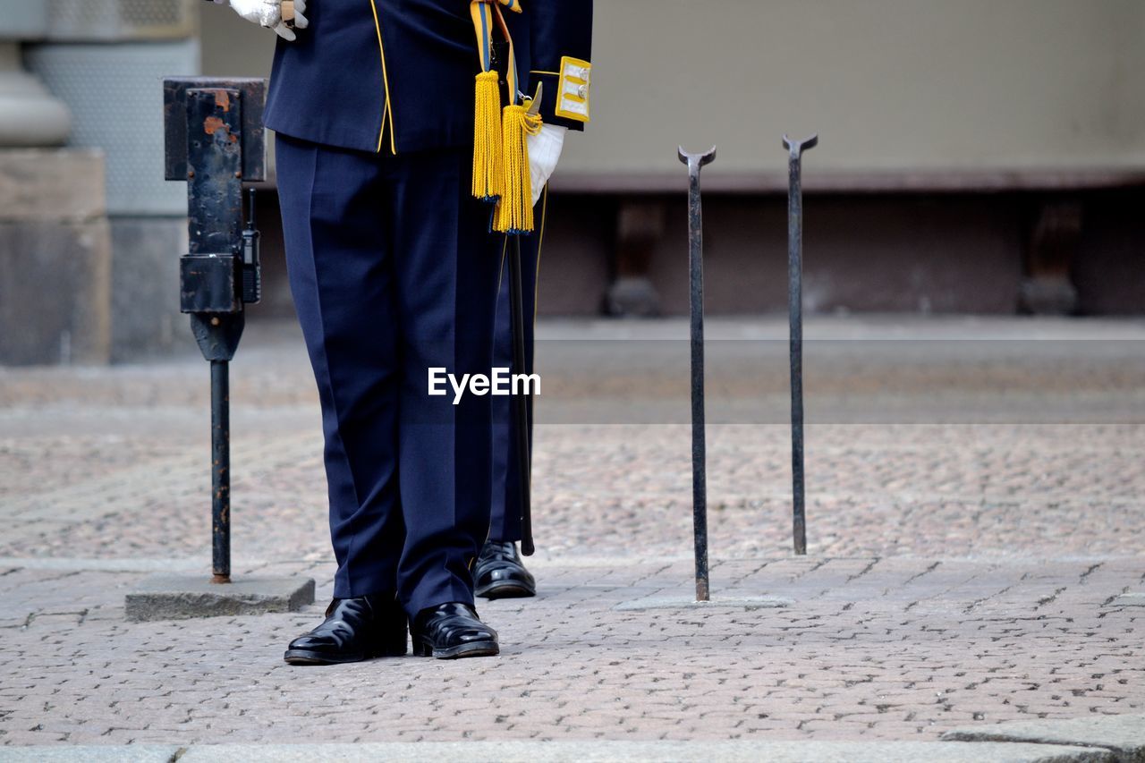 Low section of men standing in uniform on footpath