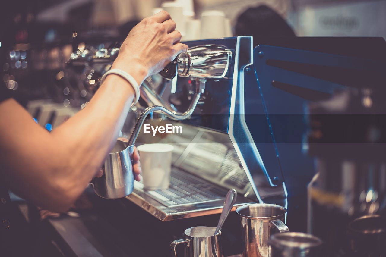 Cropped hand filling jug with drink in cafe