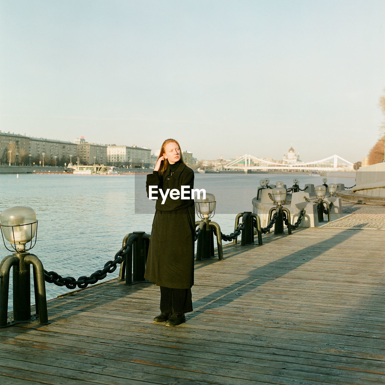 A woman stands at sunset near the bridge